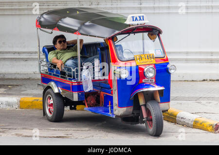 Tuk Tuk driver se reposant dans l'arrière de son taxi sur un stree à Bangkok, Thaïlande Banque D'Images