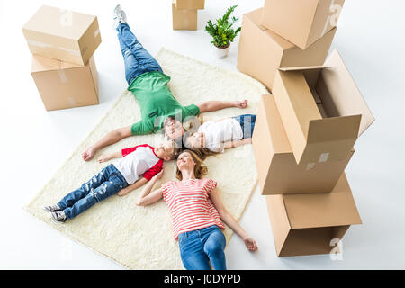 Vue de dessus du jeune famille de quatre tapis de détente après le déménagement dans la nouvelle maison Banque D'Images