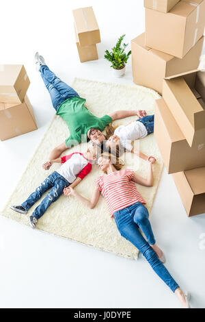 Vue de dessus du jeune famille de quatre tapis de détente après le déménagement dans la nouvelle maison Banque D'Images