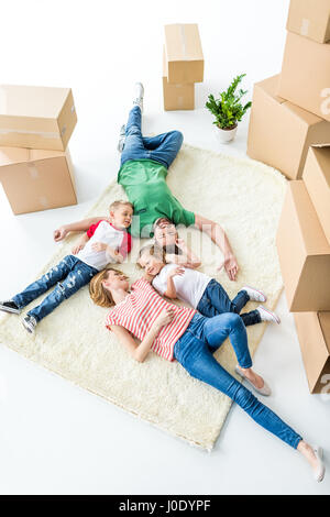 Vue de dessus de happy family sur tapis après déménagement en nouvelle maison Banque D'Images