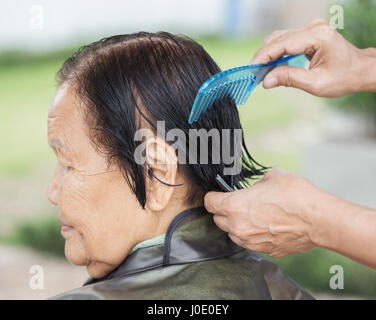 Utiliser la main peigne pour habiller les cheveux d'une femme senior Banque D'Images