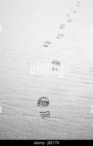 Empreintes de chaussures de randonnée sur la plage. Monochrome Banque D'Images