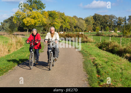 Hauts homme et femme sur des vélos sur un dutch countryroad Banque D'Images