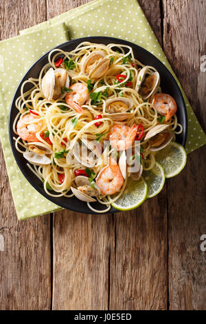 Les pâtes spaghetti délicieux avec les palourdes, les crevettes et les verts gros plan sur une assiette. Vue verticale d'en haut Banque D'Images