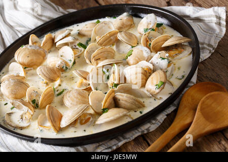 Épicerie fine food : clams compotée en crème avec l'ail et les verts close-up sur une plaque sur une table horizontale. Banque D'Images