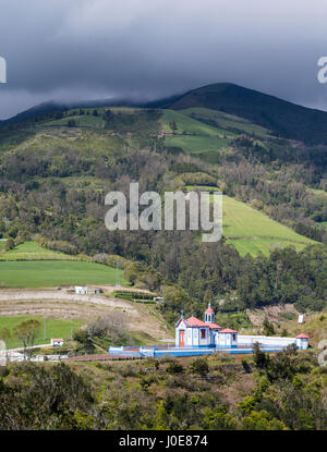 Chapelle de Nossa Senhora do Monte. Situé au-dessus de la ville cette petite chapelle brille dans le soleil comme une tempête ravage les collines derrière. Rua do Pico de C Banque D'Images