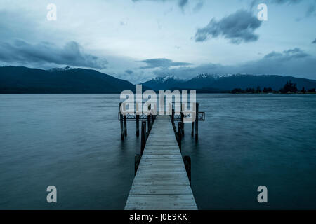 Ciel nuageux sur les montagnes, silhouette debout sur dock, Lac Te Anau, Southland, Nouvelle-Zélande Banque D'Images