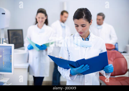 Dentiste à la recherche à l'écoute des rapports dans une clinique dentaire Banque D'Images