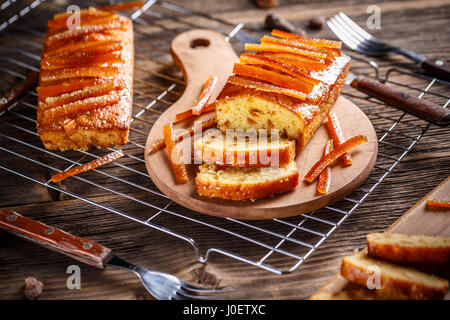 Gâteau avec le zeste d'orange confite sur planche à découper en bois Banque D'Images