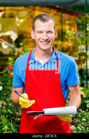Heureux homme jardinier dans une serre avec un dossier Banque D'Images