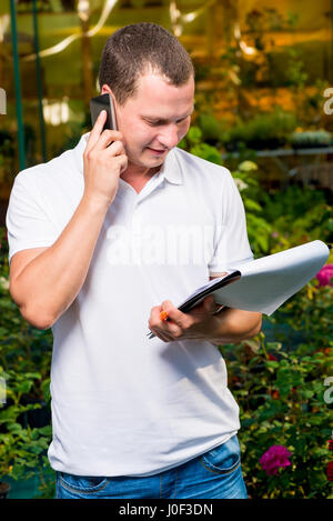 Femme propriétaire d'une entreprise de faire pousser des plantes avec un dossier et téléphone Banque D'Images
