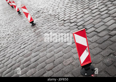 Rouge et blanc à rayures verticales attention signalisation routière se tenir dans une ligne de chemin de galets gris Banque D'Images