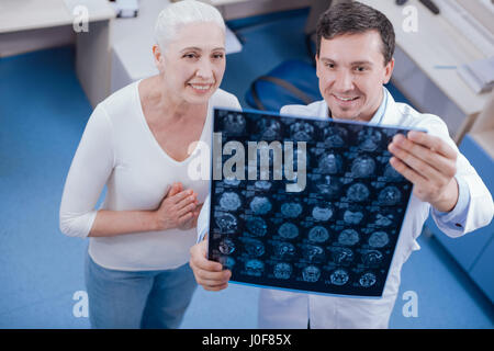 Un tel soulagement. Cheerful belle femme âgée à la recherche à l'X ray photo et d'être soulagé tout en ayant pas de déviations physiques Banque D'Images