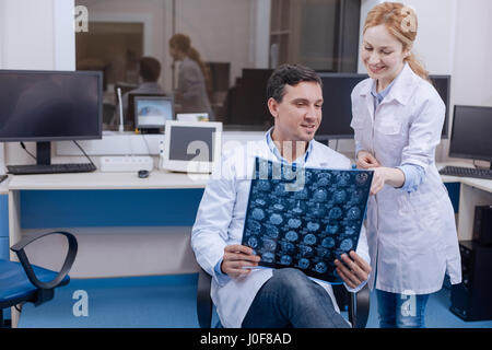 Amélioration notable. Femme médecin positive heureux, debout près de son collègue masculin et en montrant le X ray photo tout en remarquant la improveme Banque D'Images