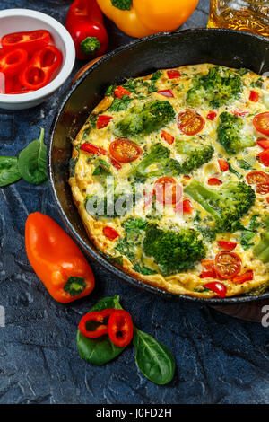 La Frittata avec brocoli, épinards, poivrons et tomates à la poêle. Genre d'omelette italienne aux légumes. Banque D'Images