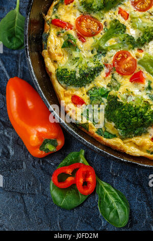 La Frittata avec brocoli, épinards, poivrons et tomates à la poêle. Genre d'omelette italienne aux légumes. Banque D'Images