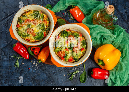 La Frittata avec brocoli, épinards, poivrons et tomates en deux formes en céramique pour la cuisson. Omelette italienne aux légumes. Vue d'en haut Banque D'Images