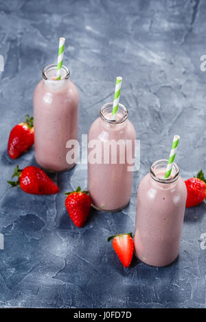 Smoothie fraise-banane dans trois bouteilles sur fond bleu Banque D'Images