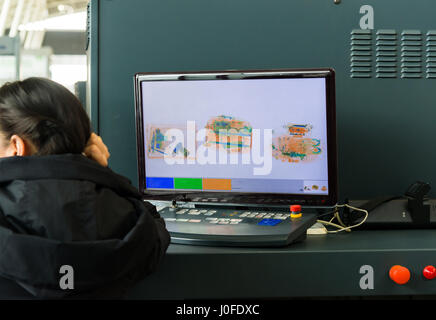 Un moniteur de rayons X à l'aéroport et la femme de service de sécurité. Banque D'Images