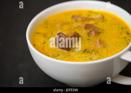 Soupe à la crème aux champignons girolles et herbes pierre noire background Banque D'Images