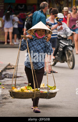 Portrait d'un vertical dame vietnamienne portant un joug traditionnel bambou à Hoi An, au Vietnam. Banque D'Images