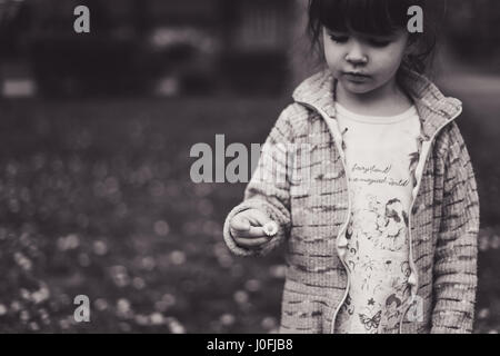 Petite fille dans un parc, fleurs Daisy en noir et blanc. Banque D'Images