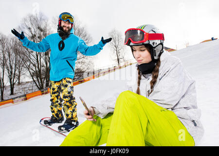 Heureux homme barbu sur la planche à la femme au smartphone snowboarder Banque D'Images