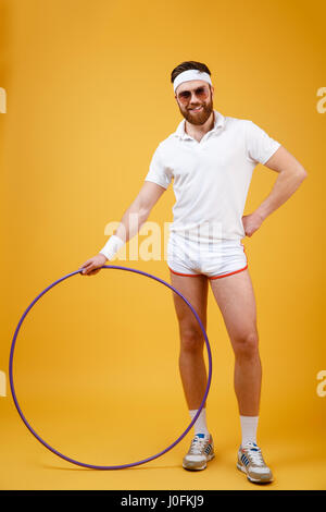 Image of young sportsman portant des lunettes avec des commandes plus isolés du cerceau de gymnastique fond jaune. En regardant la caméra. Banque D'Images