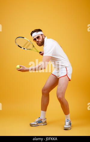 Photo de young tennis player portant des lunettes isolés sur fond jaune. En regardant la caméra. Banque D'Images