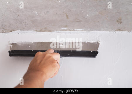 Chambre par l'amélioration de la couche de finition travailleur met en stuc sur le mur à l'aide d'une truelle de plâtrage Banque D'Images