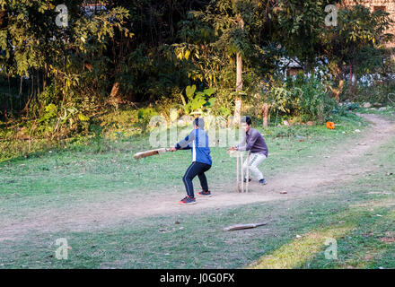 Deux garçons indiens locaux s'amusant de jouer à un jeu de cricket sur un terrain poussiéreux de Pragpur, un village historique en Kagra district, Himachal Pradesh, Inde Banque D'Images