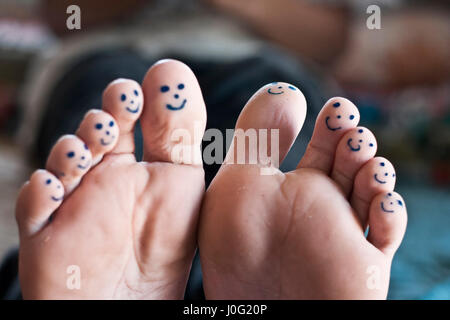 Tous les dix orteils de pieds avec smiley faces dessiné avec un stylo noir. Banque D'Images