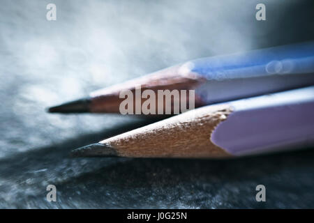 Deux crayons différents sur une surface bleutée. Banque D'Images