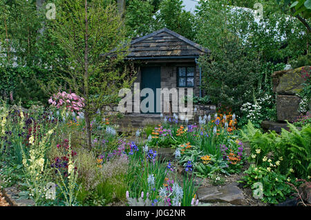 Un chalet et jardin situé dans un bois de rocaille avec un affichage coloré de fleurs Banque D'Images