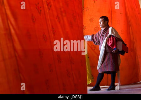 L'homme regardant à travers les rideaux à la performance, Festival, Trashichhoe Dzong, monastère, Thimphu, Bhoutan Banque D'Images