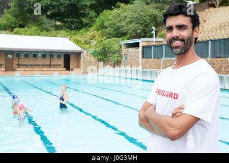 Portrait of smiling lifeguard debout avec les bras croisés dans un Banque D'Images