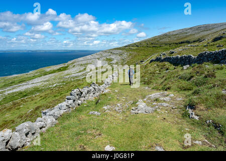 Un marcheur sur l'ancienne route verte autour de tête noire, près de Pont Fanore, le Burren, comté de Clare, Irlande Banque D'Images