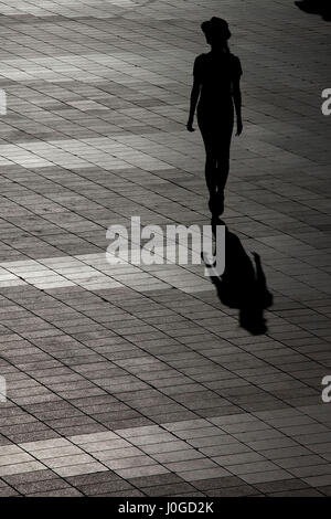 Silhouette d'une femme dans un chapeau de marcher seul Banque D'Images