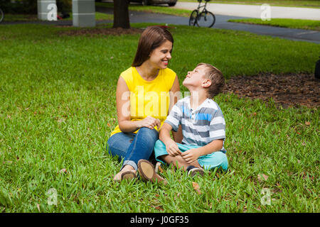 La mère et le fils assis dans l'herbe à la découverte Banque D'Images