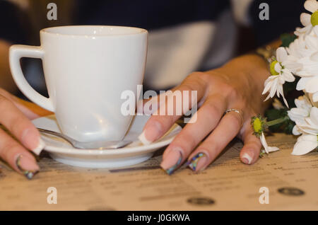 Perfect Woman's hands une touche les tasses avec un bouquet de camomille, boire un café au café dans le week-end sur le marcher Banque D'Images