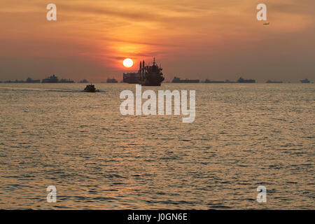 Le lever du soleil sur les navires à l'ancre dans le détroit de Singapour. Banque D'Images