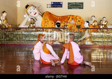 Moniales priant avant de Bouddhas en Paya Shwedagon, la plus sacrée dans la pagode bouddhiste d'Yangon, Myanmar. Banque D'Images