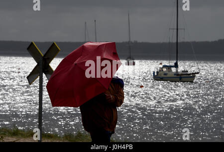 Eckernfoerde, Allemagne. 13 avr, 2017. Une femme avec un parapluie promenades le long de la mer Baltique à Eckernfoerde, Allemagne, 13 avril 2017. La météo dans le Nord n'est pas réglée et venteux. Photo : Carsten Rehder/dpa/Alamy Live News Banque D'Images