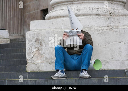Londres, Royaume-Uni. 13 avr, 2017. Un homme solitaire est assis sur les marches de la Cathédrale St Paul lire un journal portait un chapeau pointu avec le mot "Inner" écrit sur le front Crédit : Steve Parkins/Alamy Live News Banque D'Images