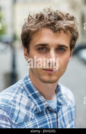 Portrait d'un jeune homme blond et bouclés avec chemise à carreaux à l'extérieur près d'un lampadaire street Banque D'Images