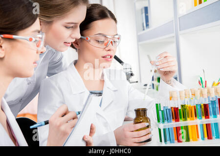 Les jeunes femmes scientifiques en laboratoire travaillant avec le réactif de laboratoire et prendre des notes Banque D'Images