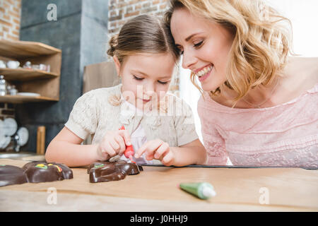 Jeune mère et sa petite fille faire le chocolat les lapins sur la cuisine Banque D'Images