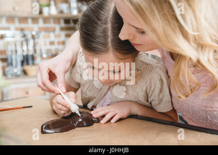 Jeune mère et sa petite fille faire lapin en chocolat sur la cuisine Banque D'Images