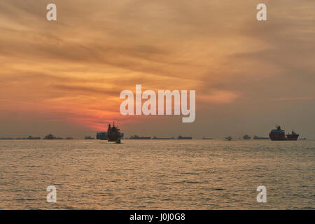 Le lever du soleil sur les navires à l'ancre dans le détroit de Singapour. Banque D'Images