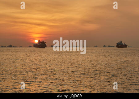 Le lever du soleil sur les navires à l'ancre dans le détroit de Singapour. Banque D'Images